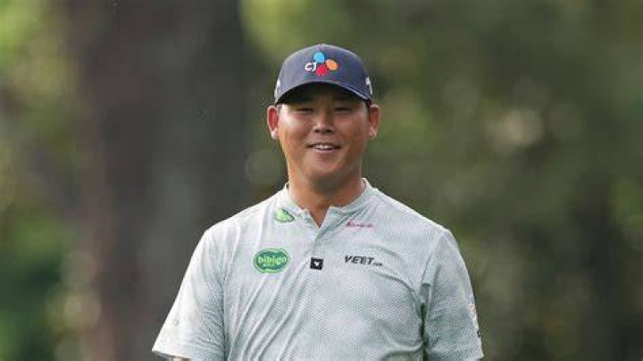 Si Woo Kim of South Korea and his caddie walk along the first hole