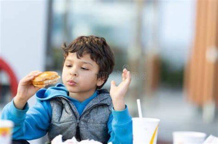 Young boy enjoying a burger on Craiyon